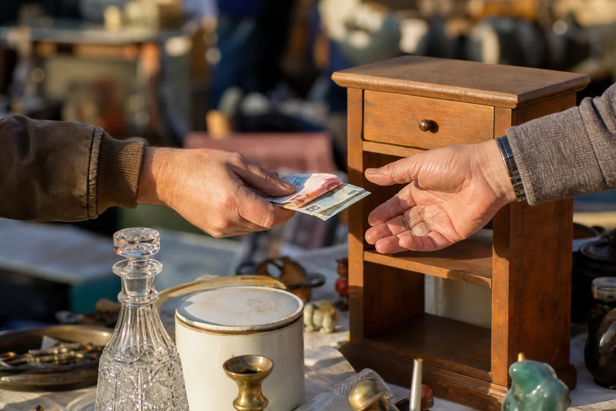 Mains échangeant des billets au-dessus d’objets chinés